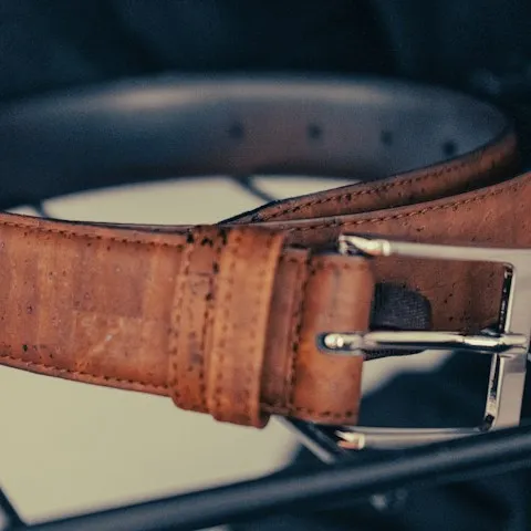 Slim leather belt coiled on a neutral surface